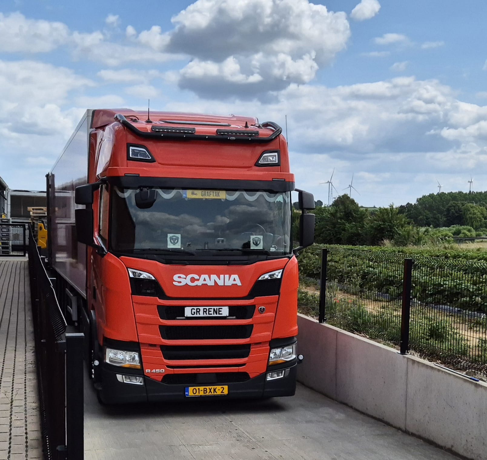 Rode Scania R450 van voren, met windmolens op de achtergrond